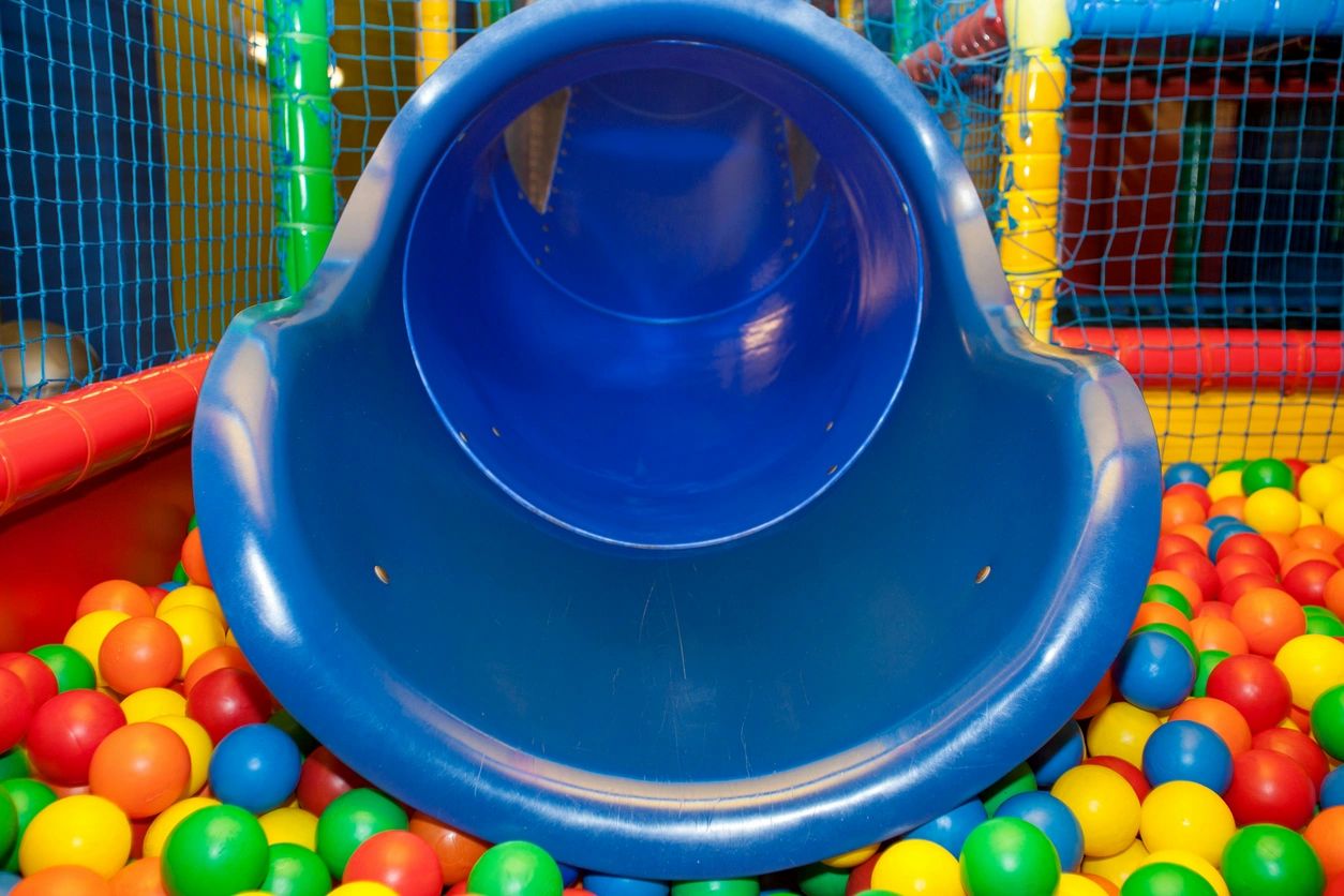A blue slide in the middle of some balls.